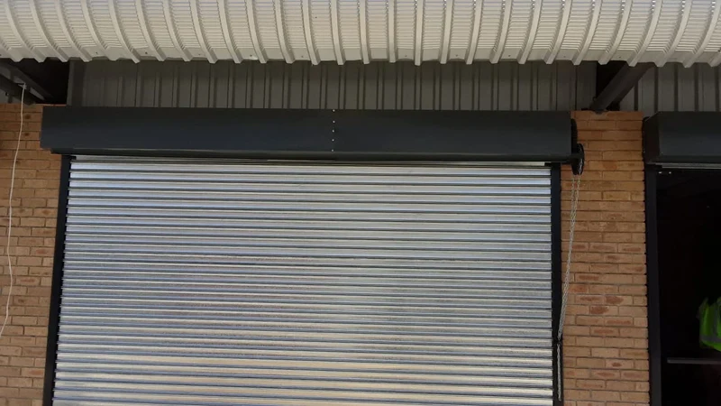 A galvanised roll-up door in a brick opening
