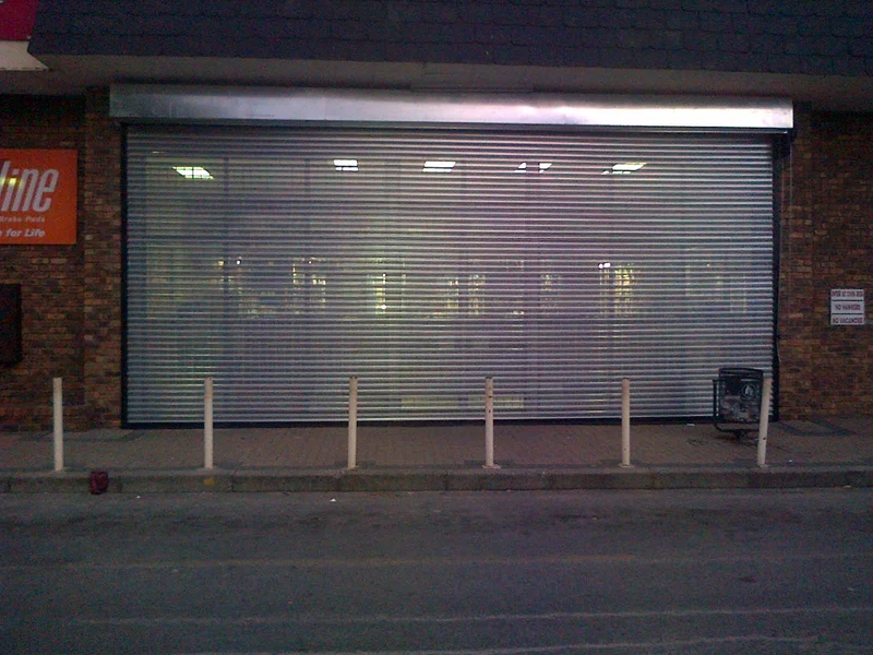 A 9 000 × 4 800 mm perforated roller shutter door closed across a retail frontage