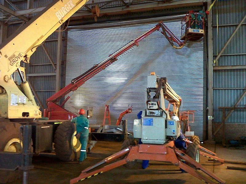 A crane lifting a 10 200 × 8 500 mm roller shutter door into place